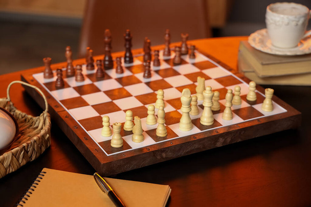 Game board with chess pieces on table in room, closeup - Fotografie, Obrázek
