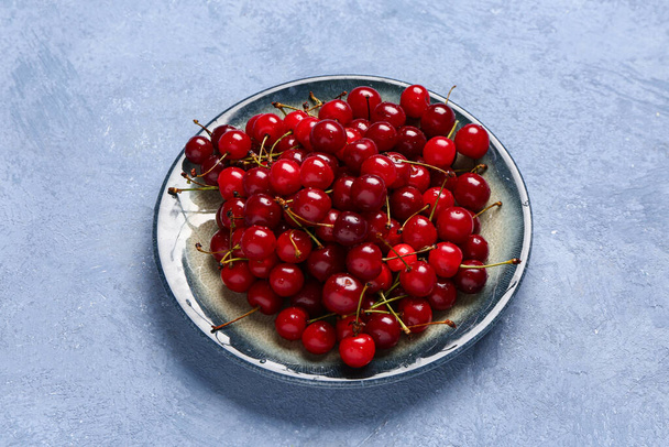 Plate with red sweet cherries on blue background - Photo, Image