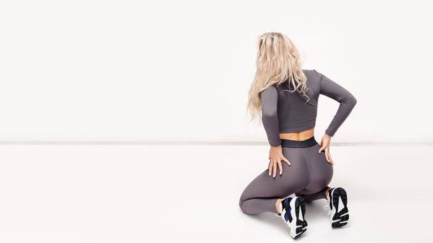 Full length view of sporty young woman in sportswear posing on the floor, isolated over white studio background. Strength, motivation, endurance concept  - Foto, Bild