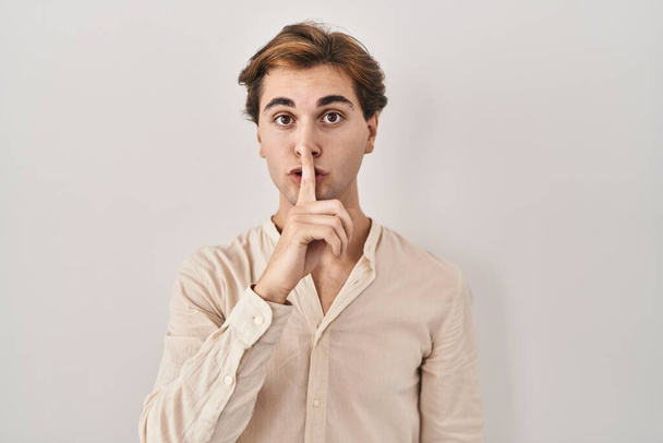Young man standing over isolated background asking to be quiet with finger on lips. silence and secret concept.  - Photo, Image