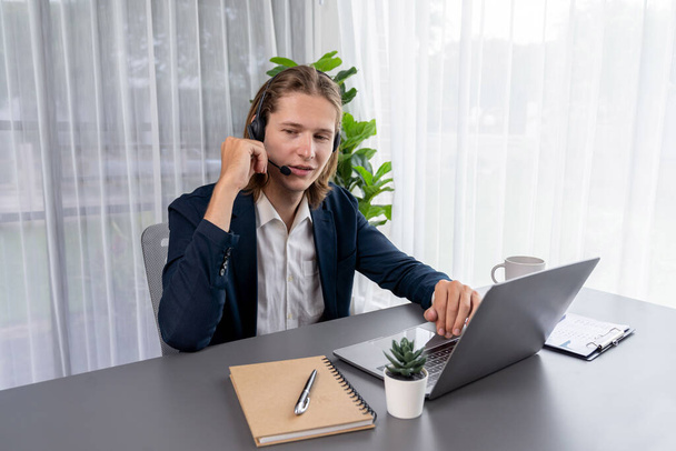 Male customer service operator or telesales agent sitting at desk in office, wearing headset and engage in conversation with client to provide support or close sales. Call center portrait. Entity - Фото, изображение