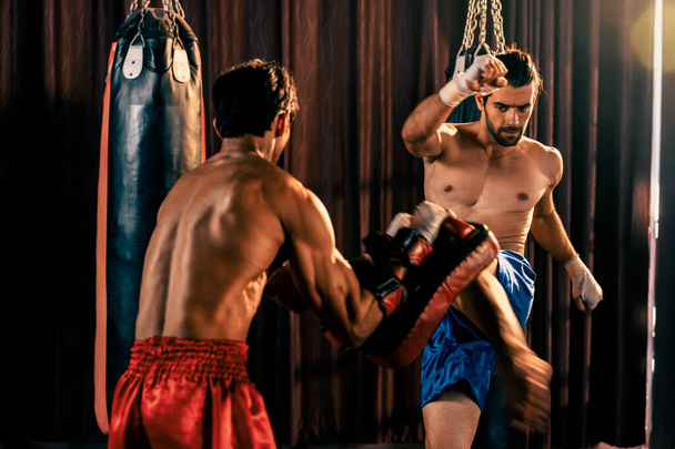 アジア人と白人ムエタイのボクサーは激しいボクシングトレーニングセッションでキック攻撃を放つ、スパーリングトレーナーにキック攻撃を提供し、ムエタイのボクシング技術とスキルを紹介します。インペトゥス - 写真・画像
