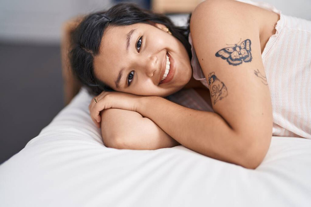 Young woman smiling confident lying on bed at bedroom - Фото, изображение