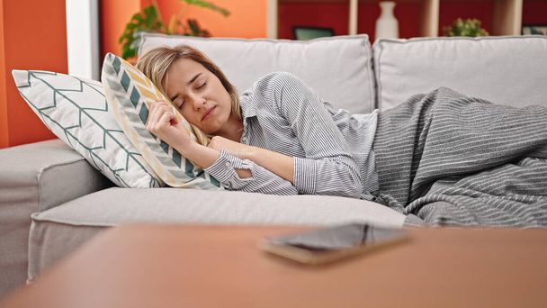 Joven mujer rubia tumbada en el sofá durmiendo en casa - Foto, Imagen