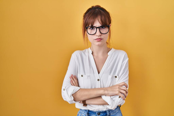 Young beautiful woman wearing casual shirt over yellow background skeptic and nervous, disapproving expression on face with crossed arms. negative person.  - Fotografie, Obrázek