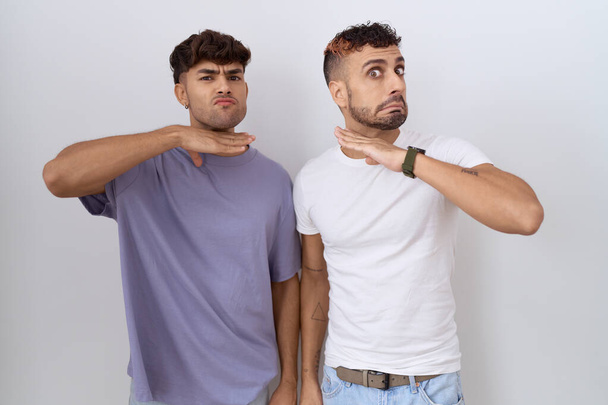 Гомосексуальна гей-пара, що стоїть над білим тлом, розрізаючи горло рукою як ніж, загрожує агресії з лютим насильством  - Фото, зображення