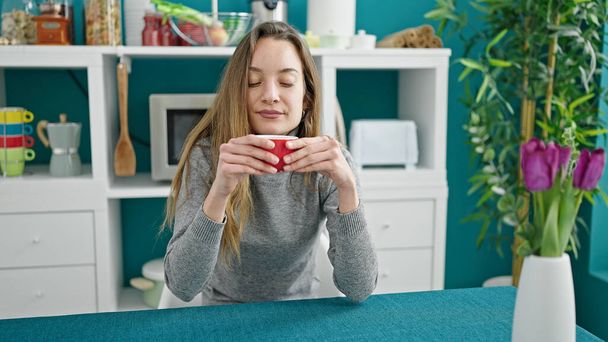 Jonge blanke vrouw die koffie drinkt zittend op tafel in de eetzaal - Foto, afbeelding