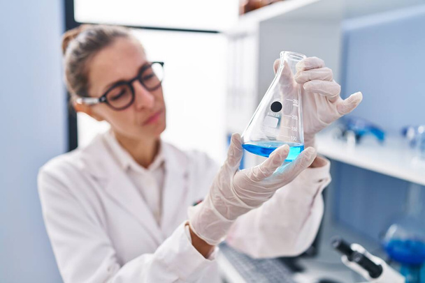 Jonge vrouw wetenschapper meten vloeistof in het laboratorium - Foto, afbeelding