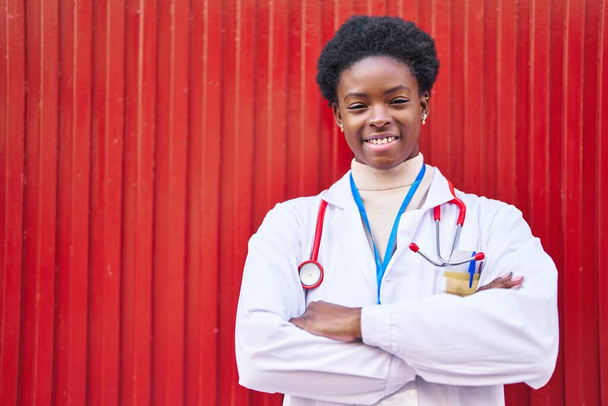 Afroamerykanka w mundurze lekarza stojąca z rękami skrzyżowanymi na ulicy - Zdjęcie, obraz