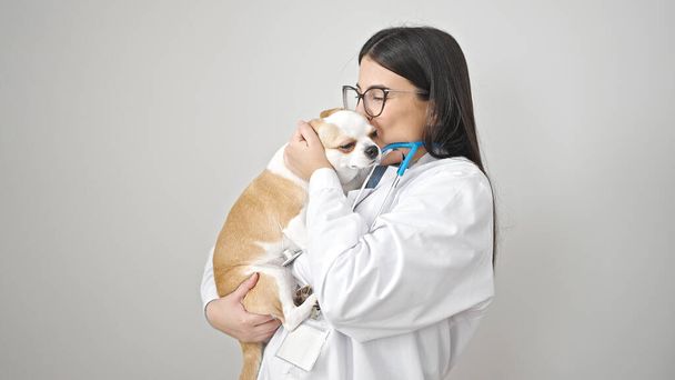 Joven mujer hispana con perro chihuahua veterinario besando perro sobre fondo blanco aislado - Foto, imagen