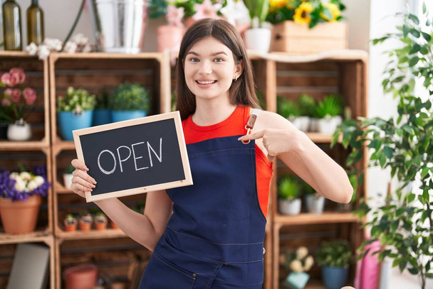Young caucasian woman working at florist holding open sign pointing finger to one self smiling happy and proud  - Foto, imagen