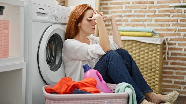 Çamaşır odasında strese girmiş genç kızıl saçlı kadın. - Fotoğraf, Görsel