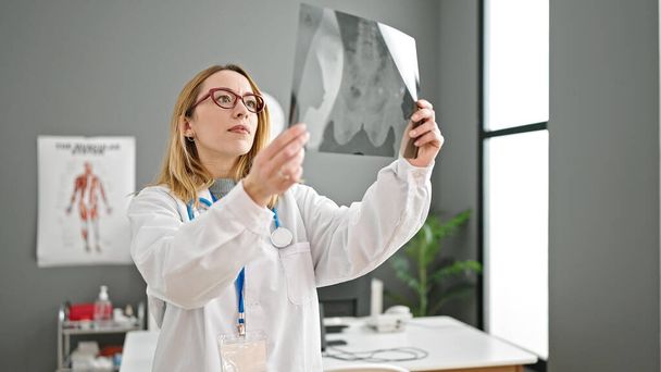 Jeune femme blonde médecin à la recherche de rayons X à la clinique - Photo, image
