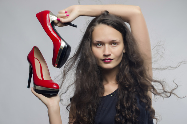 Woman in love with her high heel shoes. Beautiful girl holding her red sexy stiletto shoe. Lady shopping for shoes - Foto, imagen