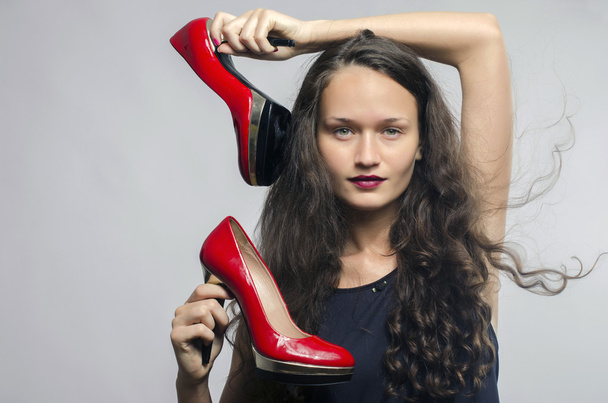 Woman in love with her high heel shoes. Beautiful girl holding her red sexy stiletto shoe. Lady shopping for shoes - Фото, зображення