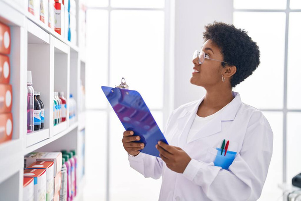 Африканська жінка - фармацевт читає документ, який працює в аптеці. - Фото, зображення