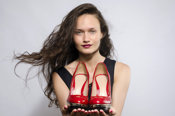 Woman in love with her high heel shoes. Beautiful girl holding her red sexy stiletto shoe. Lady shopping for shoes - Photo, image