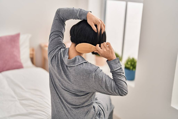 Junge Chinesin kämmt Haare auf Bett im Schlafzimmer - Foto, Bild