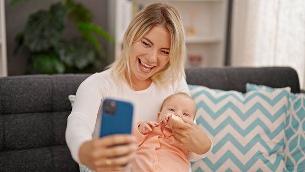 Mutter und Tochter umarmen sich und machen Selfie per Smartphone zu Hause - Foto, Bild