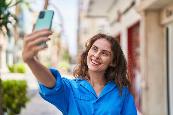 Young woman smiling confident making selfie by the smartphone at street - Foto, Bild