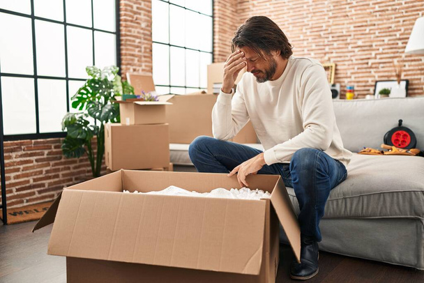 Moyen Age homme déballage boîte en carton avec expression inquiète à la nouvelle maison - Photo, image