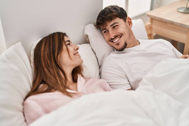 Mand και γυναίκα ζευγάρι χαμογελά αυτοπεποίθηση που βρίσκεται στο κρεβάτι στο υπνοδωμάτιο - Φωτογραφία, εικόνα