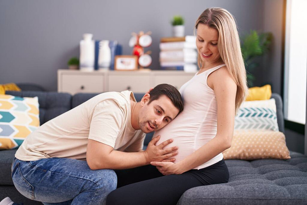 Man and woman couple listening baby sound sitting on sofa at home - Fotoğraf, Görsel