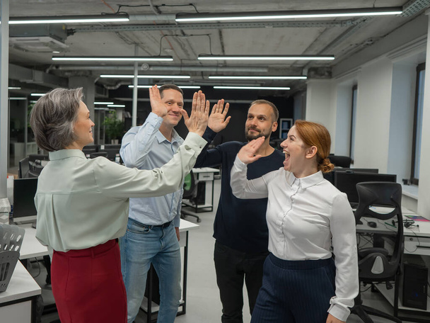 Four co-workers give a high five in the office - Photo, image