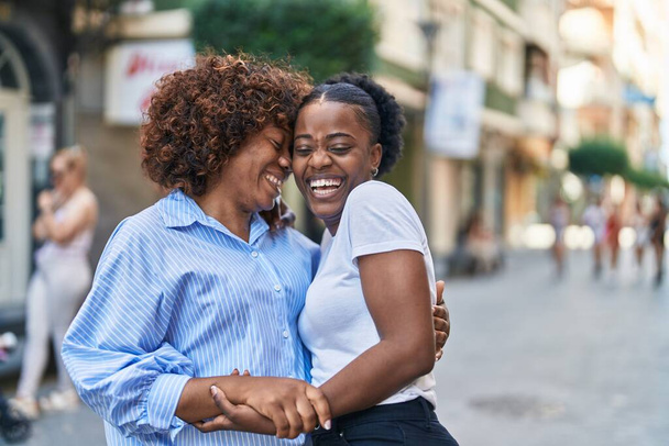 African american women mother and daughter hugging each other at street - Photo, Image