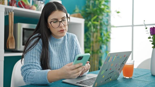 Fiatal spanyol nő használja laptop és okostelefon ebédlőben - Fotó, kép