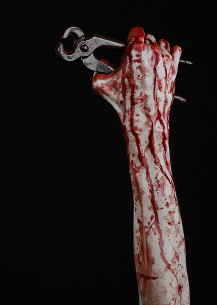 Halloween theme: bloody hand holding a pliers on a black background - Фото, зображення