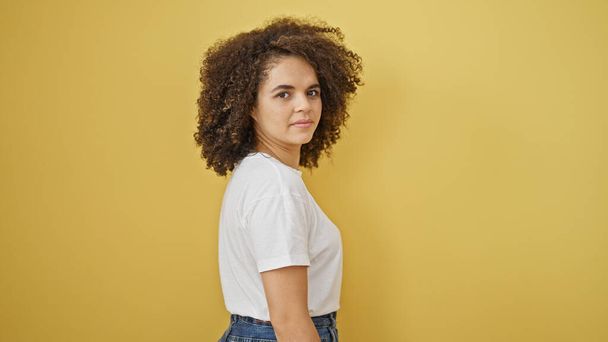 Young beautiful hispanic woman standing with serious face over isolated yellow background - Photo, Image
