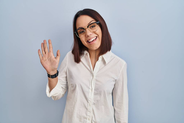 Nuori latino nainen seisoo valkoinen tausta osoittaa ylös sormet numero viisi hymyillen itsevarma ja onnellinen.  - Valokuva, kuva