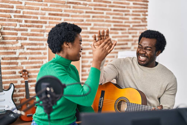 African american man and woman music group high five with hands raised up at music studio - Fotó, kép