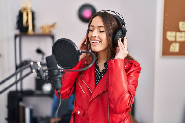 Jovem bela mulher hispânica músico sorrindo canção cantando confiante no estúdio de música - Foto, Imagem