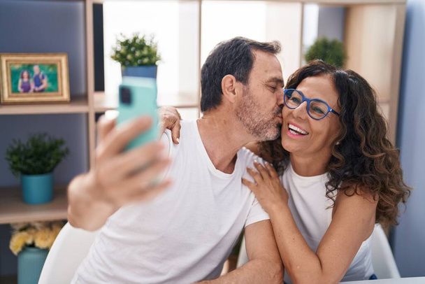 Чоловік і жінка роблять селфі за допомогою смартфона, сидячи на столі вдома
 - Фото, зображення