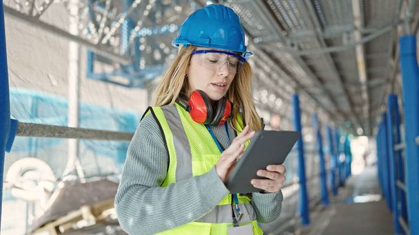 Young blonde woman builder using touchpad at street - Photo, Image