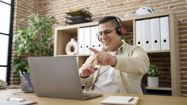 Young hispanic man business worker dancing using laptop at office - Photo, Image
