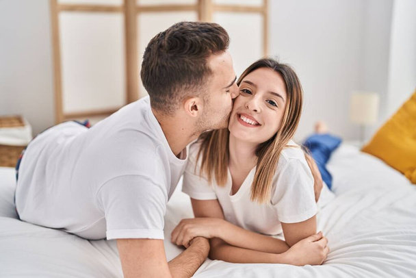 man en vrouw paar liggend op bed knuffelen elkaar en zoenen in slaapkamer - Foto, afbeelding