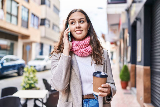 Joven hermosa mujer hispana usando smartphone bebiendo café en la calle - Foto, imagen