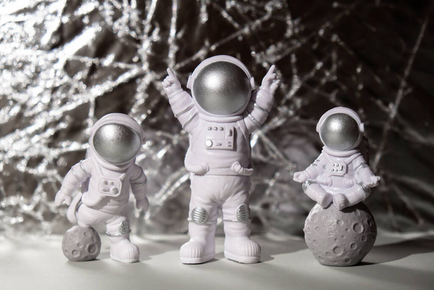 Drie Plastic speelgoed figuur astronaut op zilveren achtergrond Kopieer ruimte. Concept van reizen buiten de aarde, particuliere ruimtevaarder commerciële vluchten. Ruimtemissies en duurzaamheid - Foto, afbeelding
