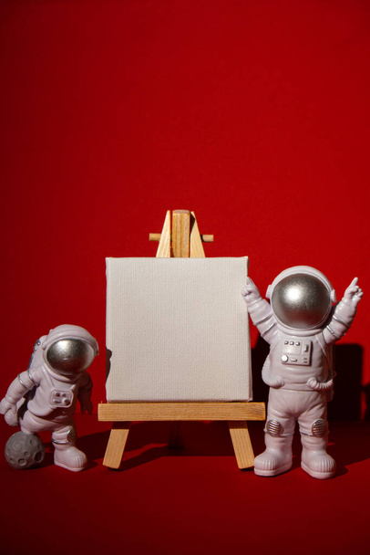 Kağıt not şablonuna sahip plastik oyuncak astronot renkli kırmızı arkaplan kopyalama uzayı metniniz için modelleme yapın. Dünya dışı seyahat kavramı, özel uzay adamı ticari uçuşları. Uzay görevleri ve - Fotoğraf, Görsel