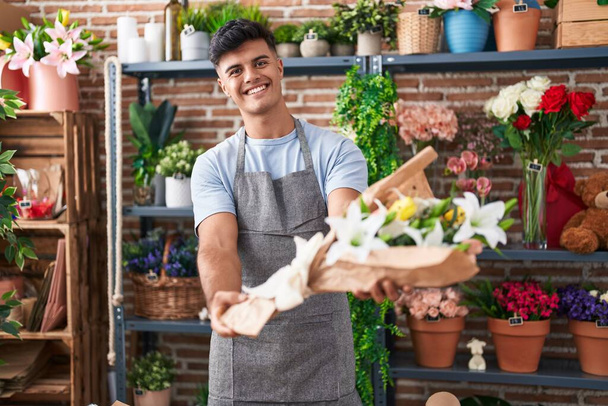 Young hispanic man florist holding bouquet of flowers at flower shop - Foto, afbeelding