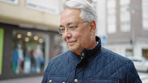 Middle age man with grey hair standing with serious expression at street - Photo, Image