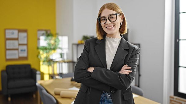 Fiatal szőke nő üzleti dolgozó mosolygós magabiztos álló karokkal keresztbe tett gesztussal az irodában - Fotó, kép