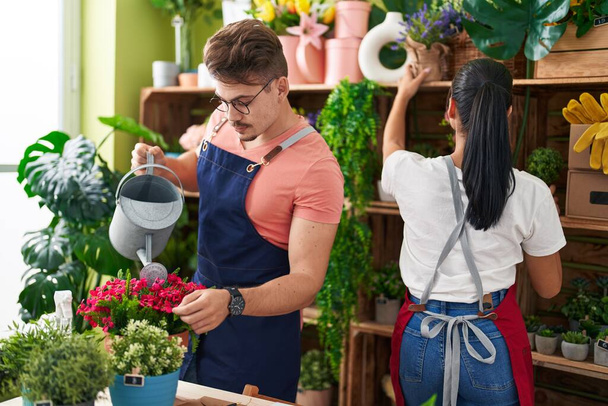 Man and woman florists watering plant working at flower shop - Photo, Image