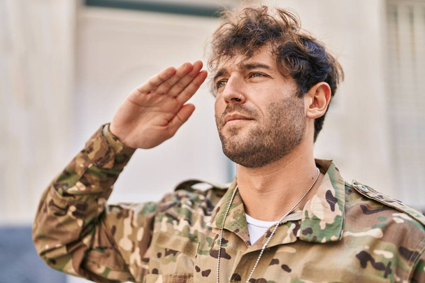Młody żołnierz wojskowy salutuje na ulicy. - Zdjęcie, obraz