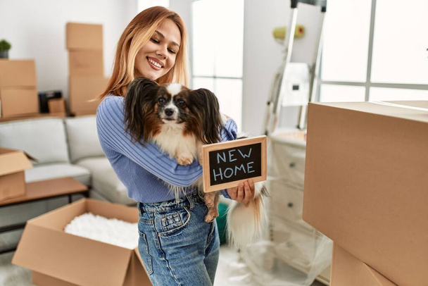 Fiatal kaukázusi nő kezében táblával ölelés kutya az új otthon - Fotó, kép
