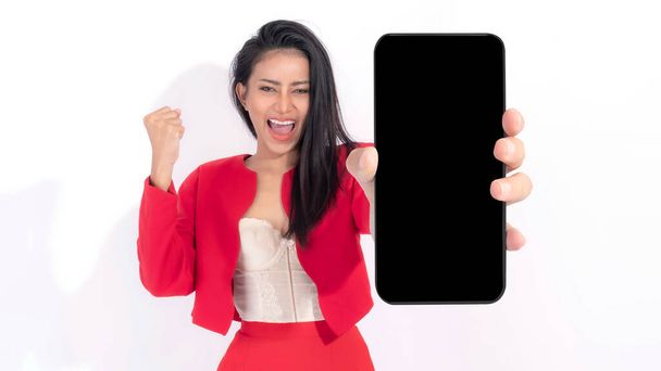 Красивая азиатская брюнетка милая девушка в красном платье, взволнованная удивленная девушка показывает большой смартфон с пустым экраном, белый экран изолирован на белом фоне, Показать макет изображения - Фото, изображение