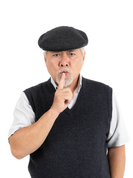 Aziatisch senior man, oude man zich serieus slecht humeur boos houdt zijn vinger in zijn mond, waardoor stilte gebaar geïsoleerd op witte achtergrond - levensstijl senior mannelijk concept - Foto, afbeelding